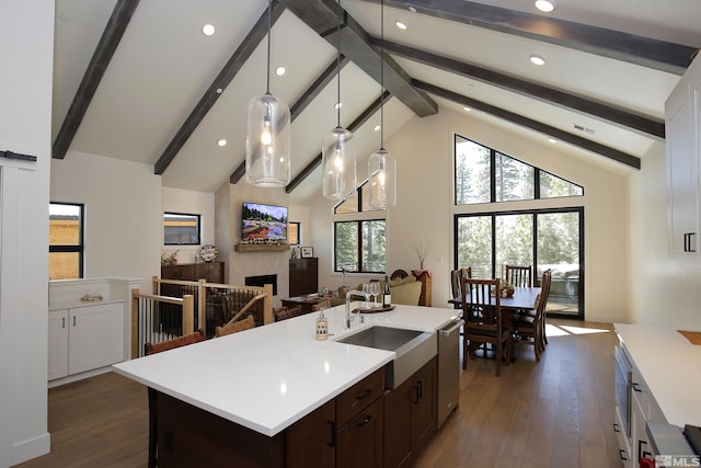 kitchen featuring dishwasher, dark wood-style floors, light countertops, a brick fireplace, and a sink