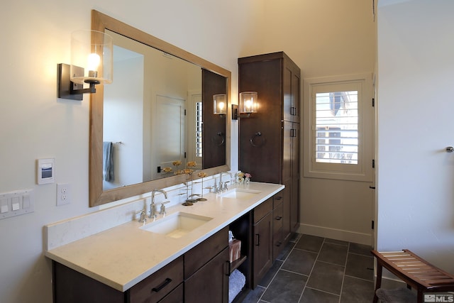 bathroom with double vanity, tile patterned flooring, a sink, and baseboards