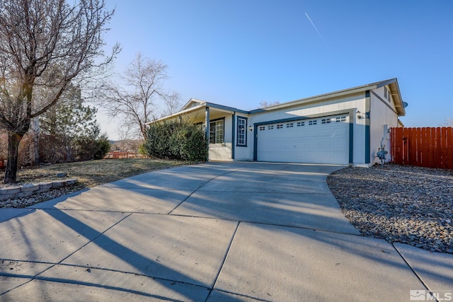 view of front of property featuring a garage, fence, and concrete driveway