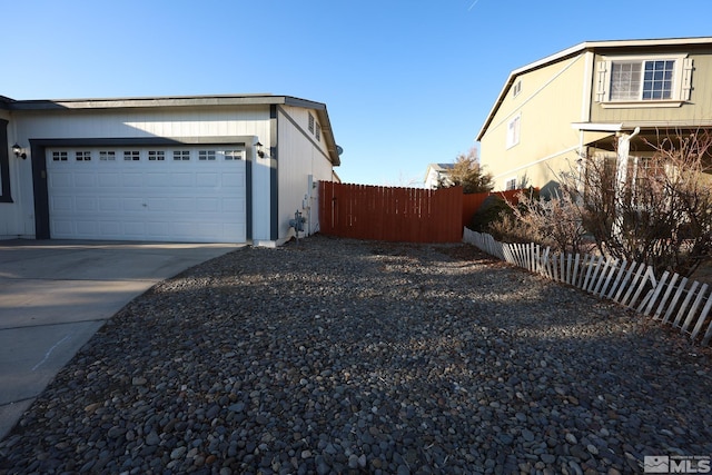 view of property exterior with driveway, an attached garage, and fence