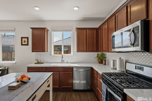 kitchen featuring tasteful backsplash, dark wood-style flooring, stainless steel appliances, light countertops, and a sink