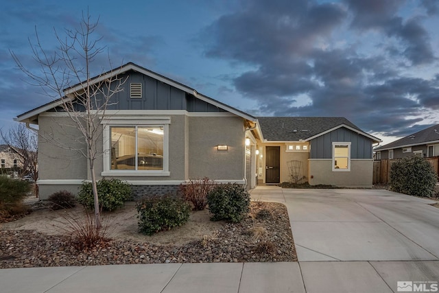 view of front of home featuring stone siding, a shingled roof, fence, and board and batten siding