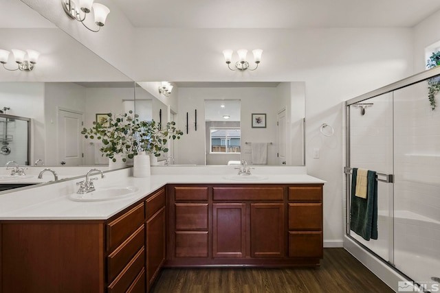 full bathroom with double vanity, a shower stall, a sink, and wood finished floors