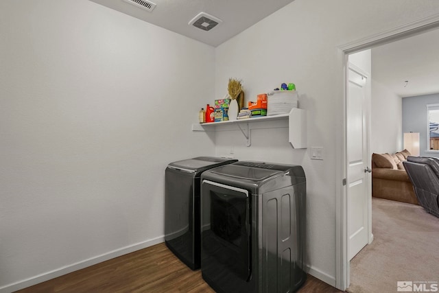 laundry area featuring laundry area, wood finished floors, washing machine and clothes dryer, and baseboards