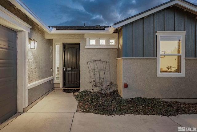 property entrance featuring board and batten siding and stucco siding