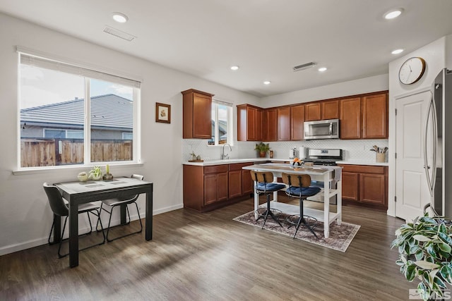 kitchen with visible vents, decorative backsplash, appliances with stainless steel finishes, dark wood-type flooring, and light countertops