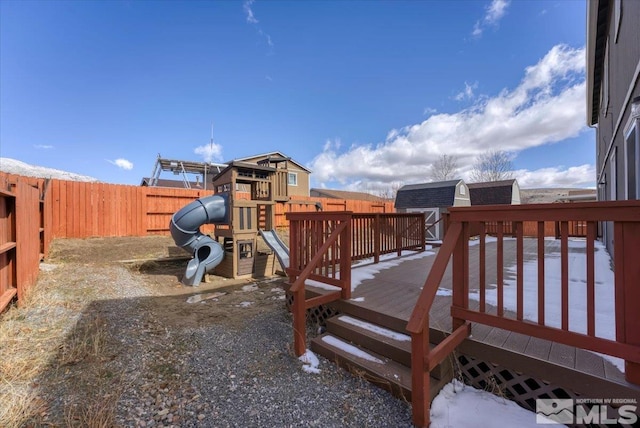 view of jungle gym featuring a shed, an outdoor structure, a fenced backyard, and a wooden deck