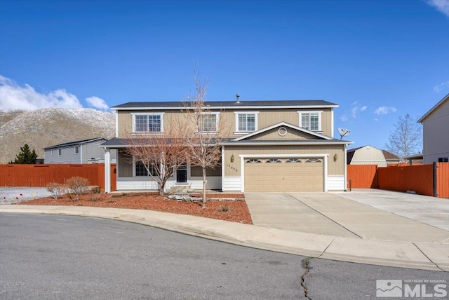 traditional-style house featuring concrete driveway, an attached garage, and fence