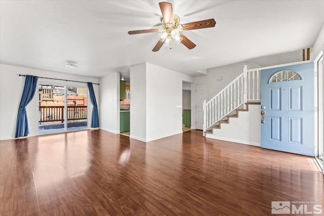 unfurnished living room with wood finished floors, ceiling fan, baseboards, and stairs