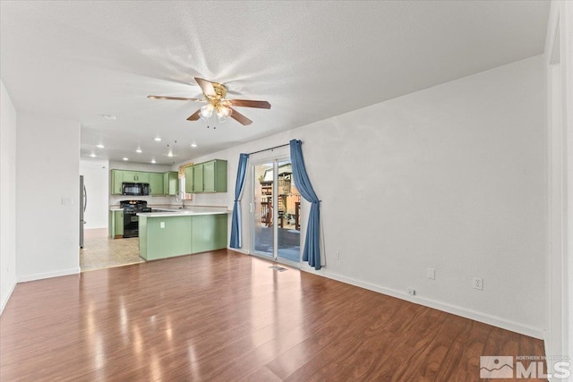 unfurnished living room with baseboards, visible vents, a ceiling fan, and wood finished floors