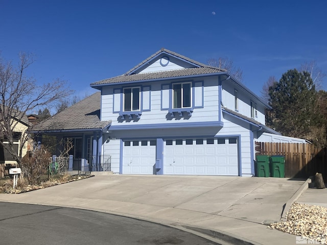 traditional home with an attached garage, fence, concrete driveway, and a tiled roof