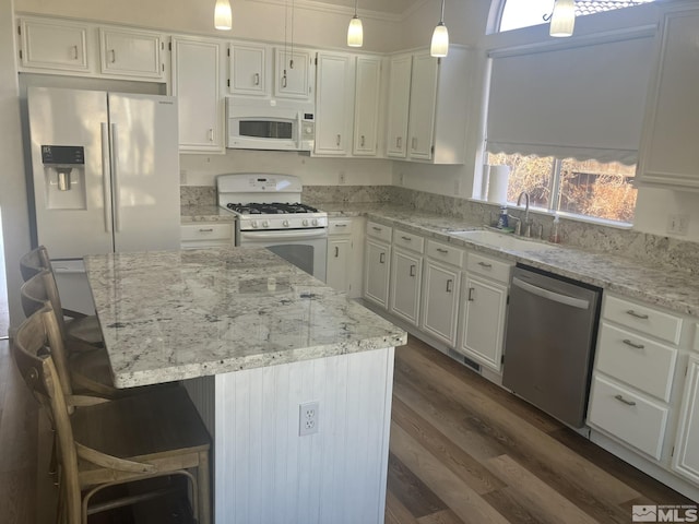 kitchen featuring light stone counters, white appliances, white cabinets, and a sink