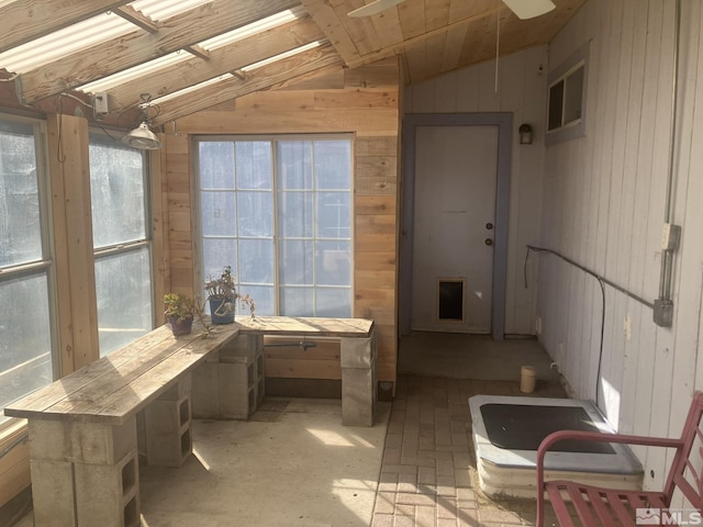 interior space featuring vaulted ceiling and wood walls