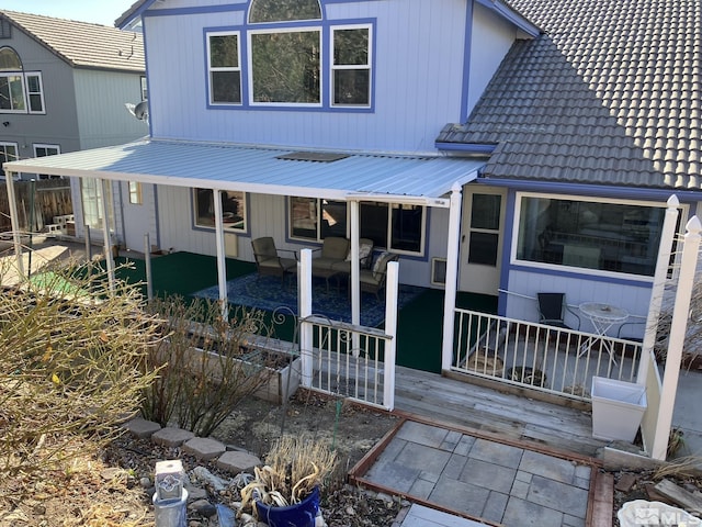 back of property with a tile roof, metal roof, and a patio