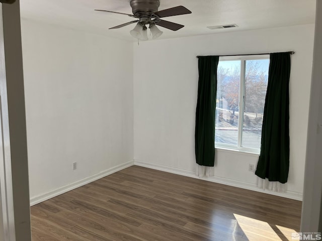 empty room featuring baseboards, visible vents, ceiling fan, and wood finished floors