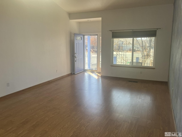 unfurnished room featuring baseboards, visible vents, and wood finished floors