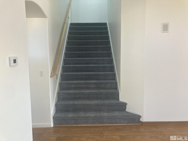 stairs with baseboards, arched walkways, and wood finished floors