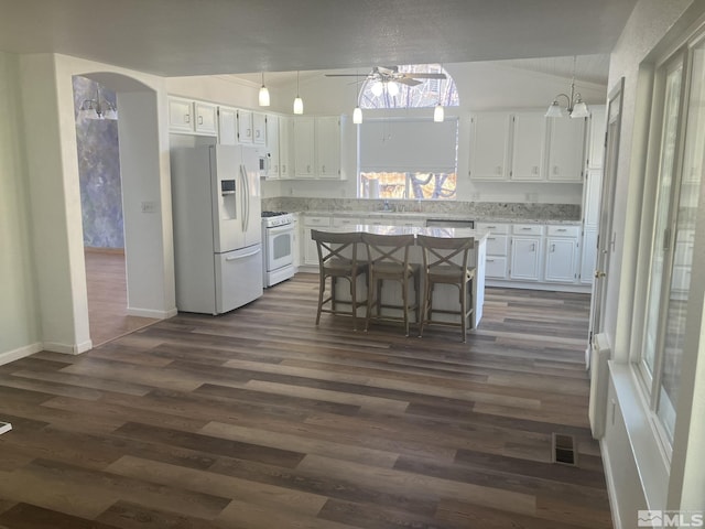 kitchen featuring white appliances, visible vents, arched walkways, and dark wood finished floors