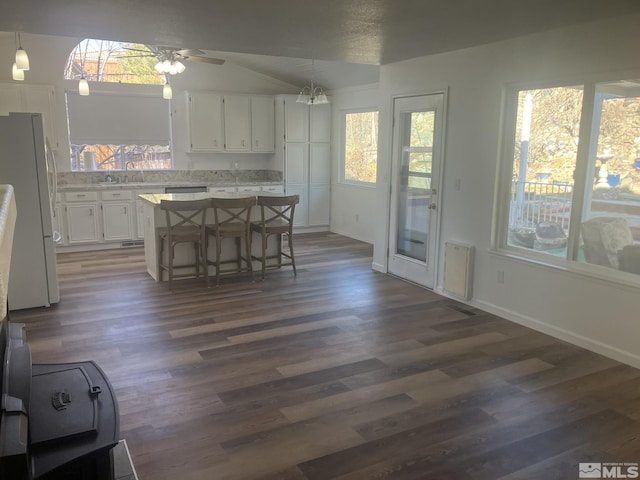 kitchen featuring dark wood-style floors, a kitchen island, freestanding refrigerator, and white cabinetry