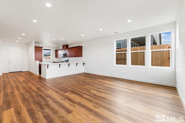 unfurnished living room featuring baseboards, wood finished floors, and recessed lighting