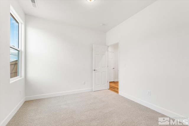 empty room featuring carpet flooring, visible vents, and baseboards