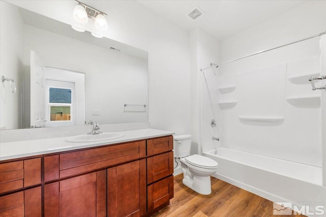 full bath with toilet, vanity, wood finished floors, and visible vents