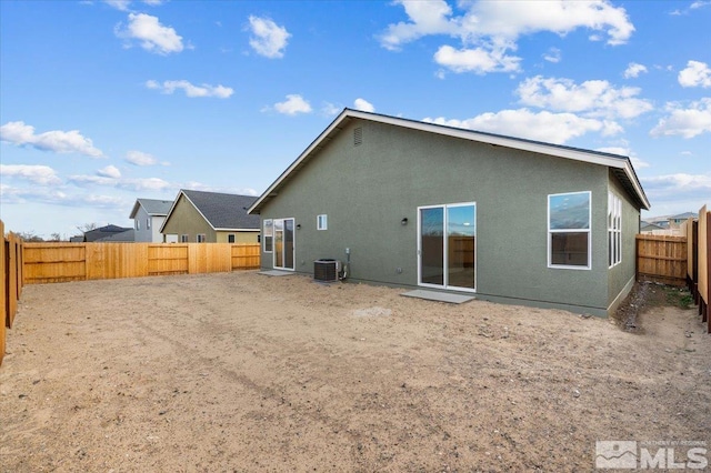 back of house featuring central AC, a fenced backyard, and stucco siding