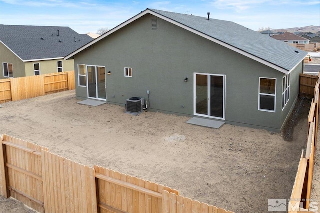 back of house with central AC unit, roof with shingles, a fenced backyard, and stucco siding