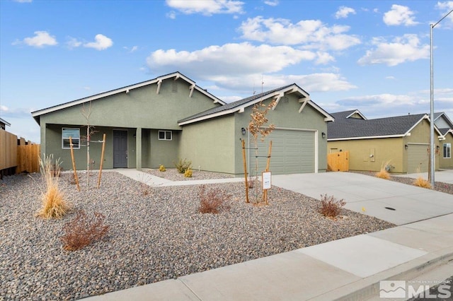 ranch-style house with a garage, concrete driveway, fence, and stucco siding