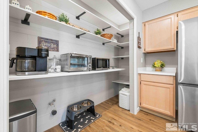 kitchen with light wood-style flooring, stainless steel appliances, open shelves, light countertops, and light brown cabinetry