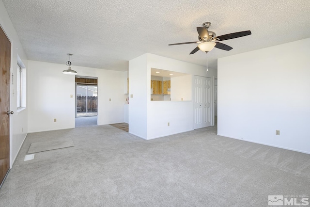 empty room featuring carpet, baseboards, ceiling fan, and a textured ceiling