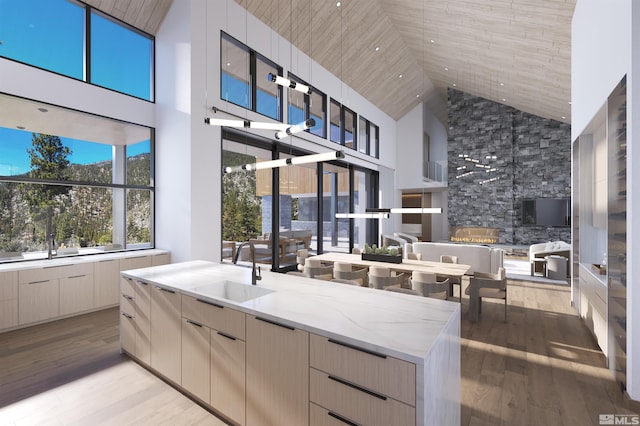 kitchen with light wood-type flooring, modern cabinets, light stone counters, and a sink