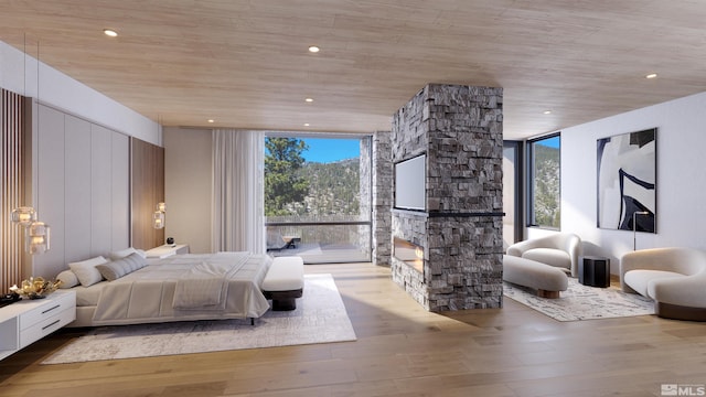 bedroom with expansive windows, a stone fireplace, and wood finished floors