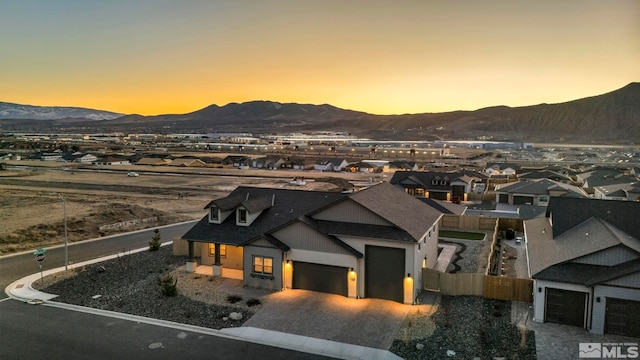 view of front facade with decorative driveway, a mountain view, an attached garage, and fence