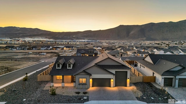 view of front of house with a garage, a residential view, fence, decorative driveway, and a mountain view