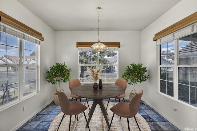 dining room with stone tile flooring, a healthy amount of sunlight, and baseboards