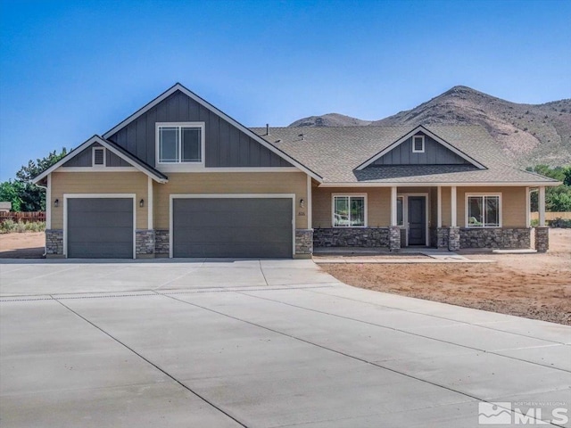 craftsman-style house featuring a mountain view, board and batten siding, concrete driveway, and stone siding