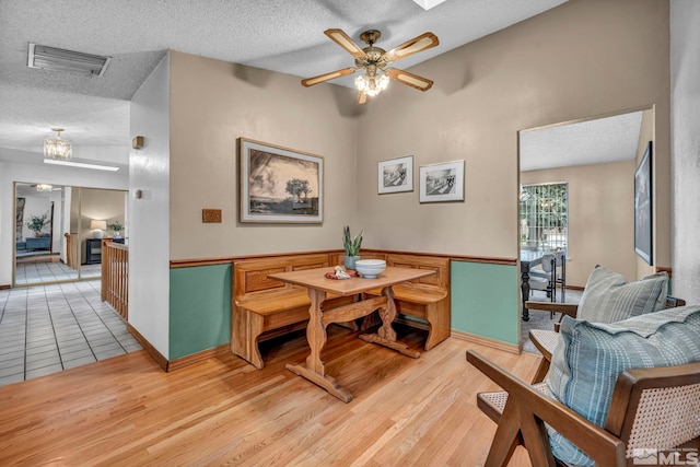 dining area with visible vents, light wood-style flooring, a textured ceiling, and ceiling fan