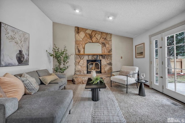 carpeted living room featuring lofted ceiling, a fireplace, visible vents, and a textured ceiling