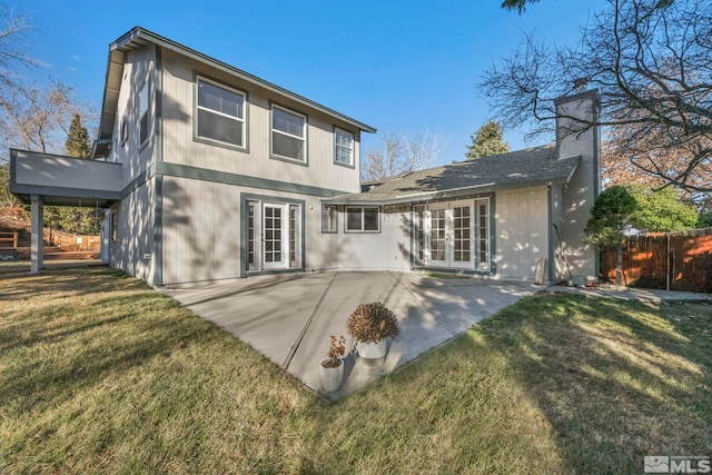 rear view of house with fence, french doors, a yard, a chimney, and a patio area