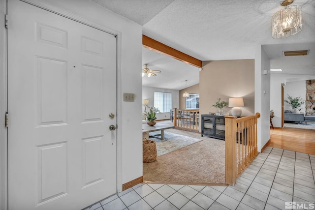 entrance foyer featuring lofted ceiling with beams, visible vents, a textured ceiling, and light tile patterned flooring