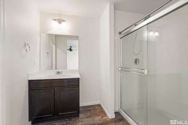 full bath featuring vanity, wood finished floors, a stall shower, and baseboards