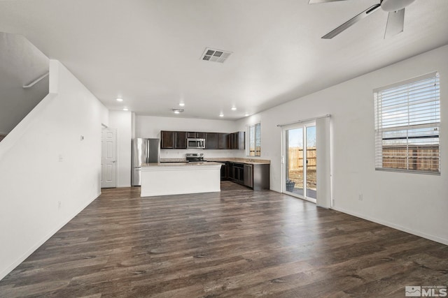 kitchen with visible vents, a kitchen island, dark wood-style flooring, stainless steel appliances, and dark brown cabinetry