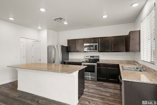 kitchen featuring a sink, dark wood finished floors, a center island, stainless steel appliances, and dark brown cabinetry