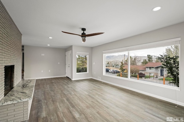 unfurnished living room featuring wood finished floors, recessed lighting, a fireplace, and baseboards