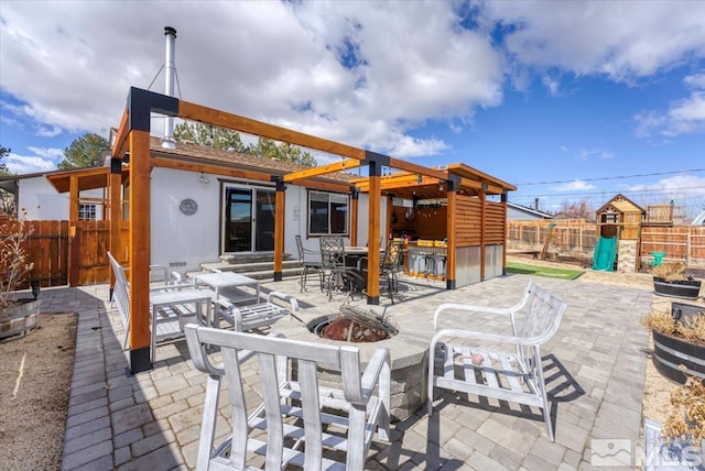 view of patio featuring fence, a fire pit, and a playground