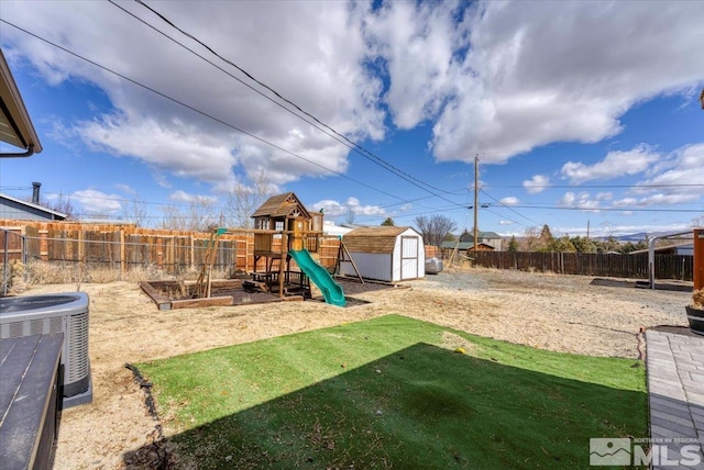 view of yard featuring a storage unit, a fenced backyard, a playground, an outdoor structure, and central AC unit