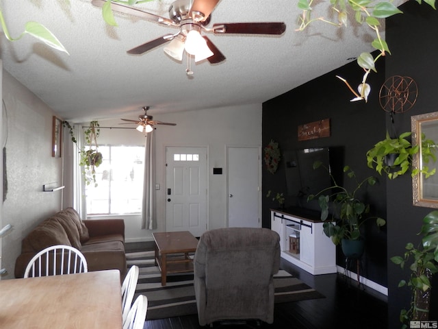 living room featuring a textured ceiling, wood finished floors, a ceiling fan, and vaulted ceiling