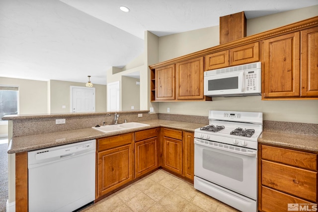 kitchen with white appliances, a peninsula, brown cabinets, and a sink