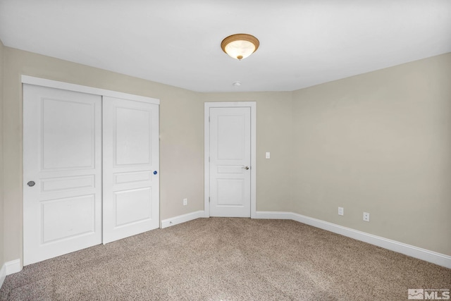 unfurnished bedroom with carpet flooring, baseboards, and a closet